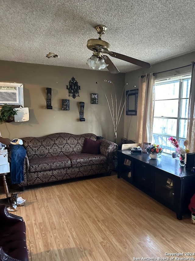 living room with ceiling fan, light hardwood / wood-style floors, a textured ceiling, and a wall mounted AC