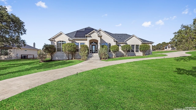 view of front of property with solar panels and a front lawn