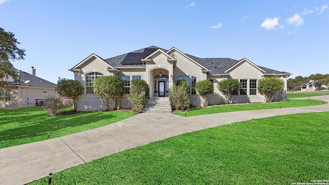 ranch-style house featuring a front yard and solar panels