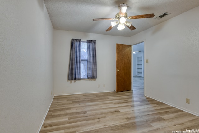 empty room with ceiling fan, light hardwood / wood-style flooring, and a textured ceiling