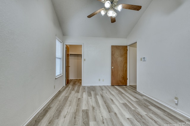 unfurnished bedroom with ceiling fan, a spacious closet, light hardwood / wood-style floors, lofted ceiling, and a closet