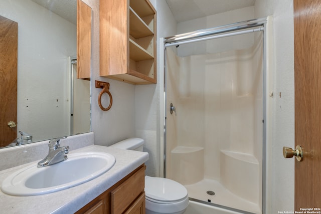 bathroom featuring vanity, toilet, a textured ceiling, and walk in shower