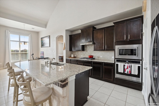 kitchen featuring stainless steel appliances, sink, light tile patterned floors, a center island with sink, and lofted ceiling