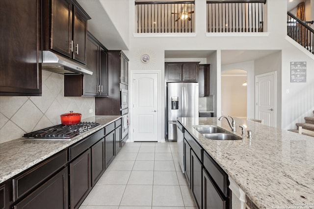 kitchen featuring backsplash, sink, light tile patterned floors, appliances with stainless steel finishes, and light stone counters