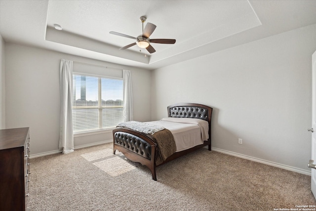 bedroom featuring a tray ceiling, ceiling fan, and light carpet