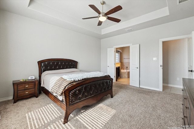 bedroom featuring ceiling fan, a raised ceiling, and ensuite bath