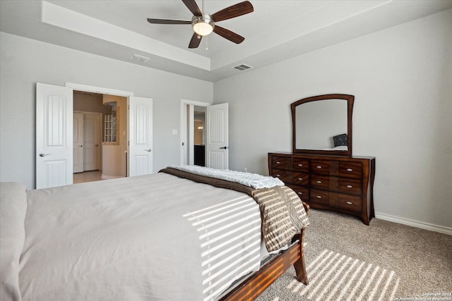 bedroom with ceiling fan, a raised ceiling, and light colored carpet