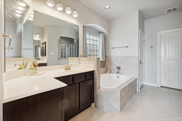 bathroom with tile patterned flooring, vanity, and tiled bath