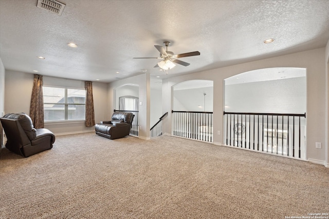 living area with carpet flooring, ceiling fan, and a textured ceiling