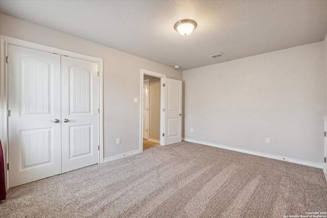 unfurnished bedroom with carpet floors, a textured ceiling, and a closet