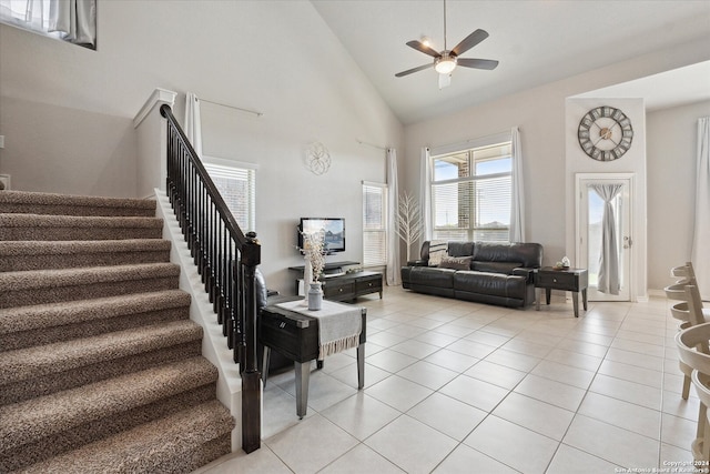 tiled living room with ceiling fan and high vaulted ceiling