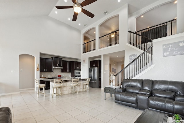 tiled living room featuring ceiling fan and high vaulted ceiling