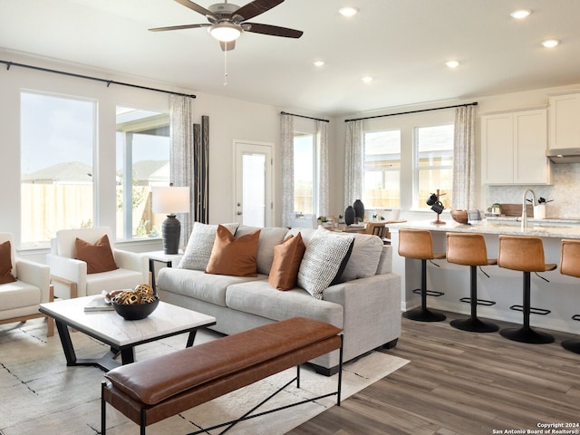 living room featuring sink, dark wood-type flooring, a wealth of natural light, and ceiling fan