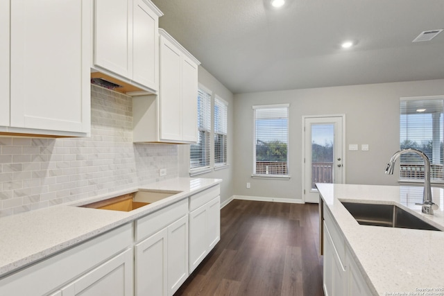 kitchen with light stone counters, backsplash, sink, and white cabinets