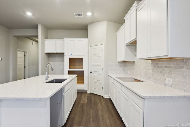 kitchen with white cabinetry, sink, and a kitchen island with sink