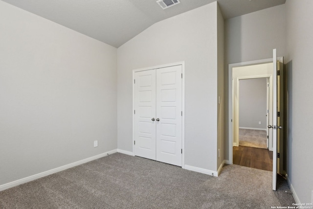 unfurnished bedroom featuring lofted ceiling, a closet, and carpet