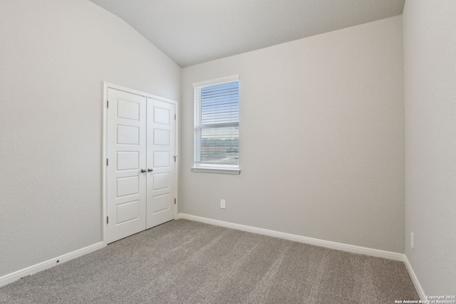 unfurnished room featuring carpet flooring and vaulted ceiling