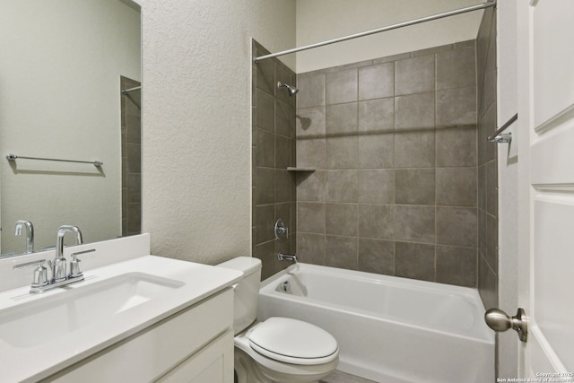 full bathroom featuring tiled shower / bath, vanity, and toilet