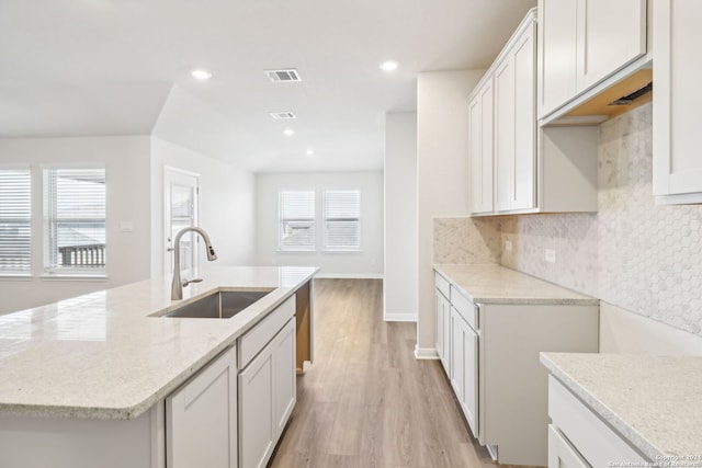 kitchen featuring a wealth of natural light, light hardwood / wood-style flooring, a kitchen island with sink, and sink