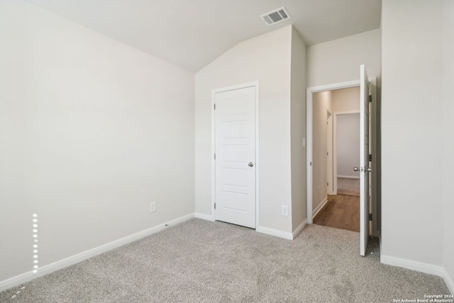 unfurnished bedroom featuring light carpet and vaulted ceiling