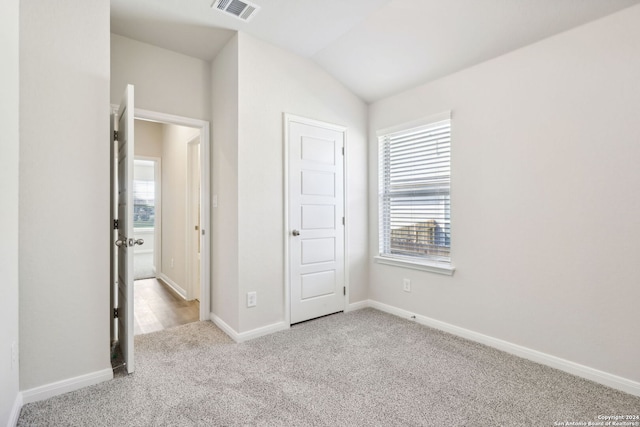 unfurnished bedroom featuring light carpet and lofted ceiling