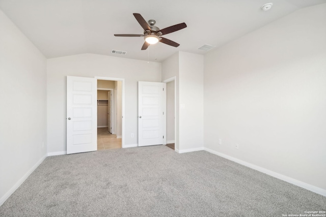 unfurnished bedroom with ceiling fan, light colored carpet, a walk in closet, and a closet