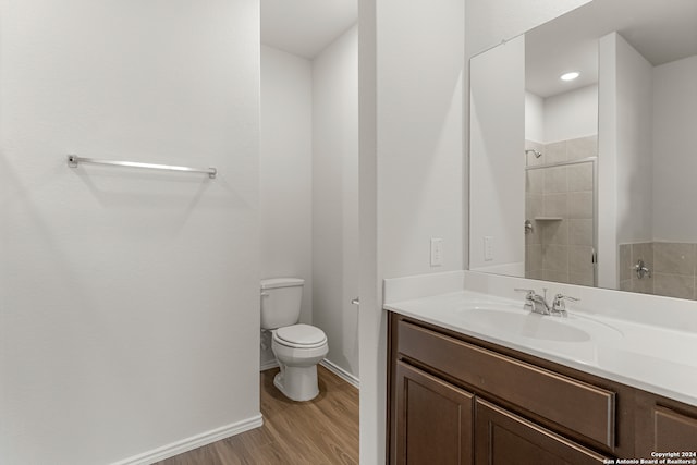 bathroom featuring a tile shower, vanity, wood-type flooring, and toilet