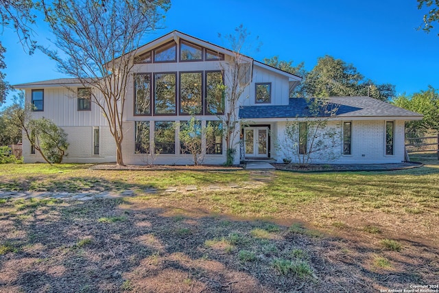 back of property featuring french doors and a lawn