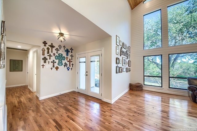 entryway featuring beamed ceiling, french doors, high vaulted ceiling, and light hardwood / wood-style flooring