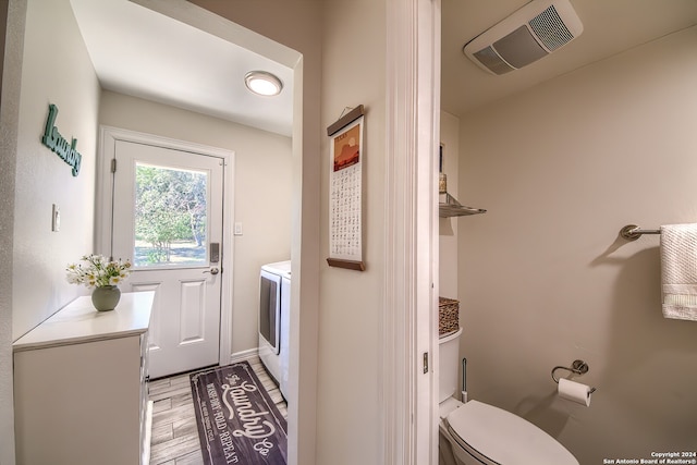 bathroom with hardwood / wood-style floors, independent washer and dryer, and toilet