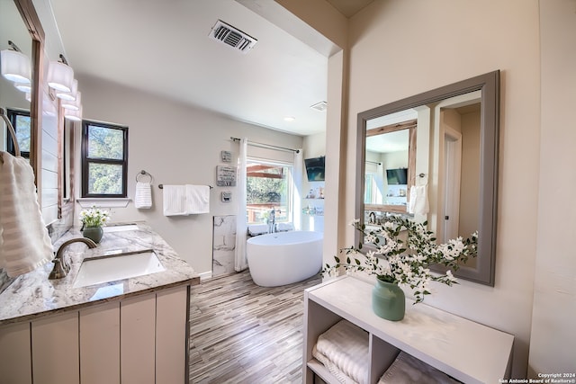 bathroom featuring hardwood / wood-style floors, vanity, and a tub