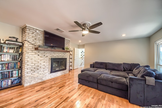 living room featuring a brick fireplace, light hardwood / wood-style flooring, and ceiling fan