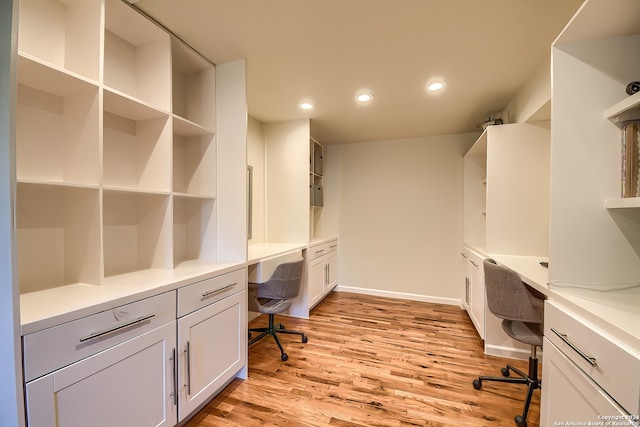 home office with light hardwood / wood-style flooring and built in desk