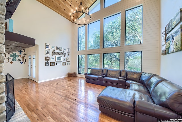 living room featuring a chandelier, high vaulted ceiling, light hardwood / wood-style floors, and wooden ceiling