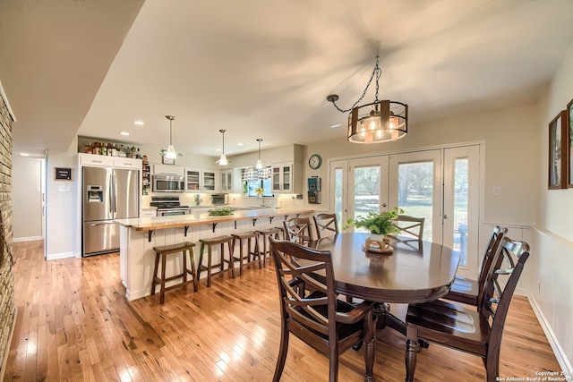 dining room with a chandelier, french doors, light hardwood / wood-style floors, and sink