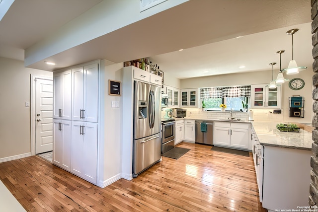 kitchen with white cabinetry, sink, stainless steel appliances, decorative backsplash, and light wood-type flooring