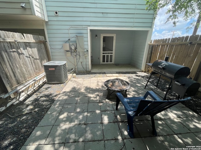 view of patio with central air condition unit, grilling area, and a fire pit