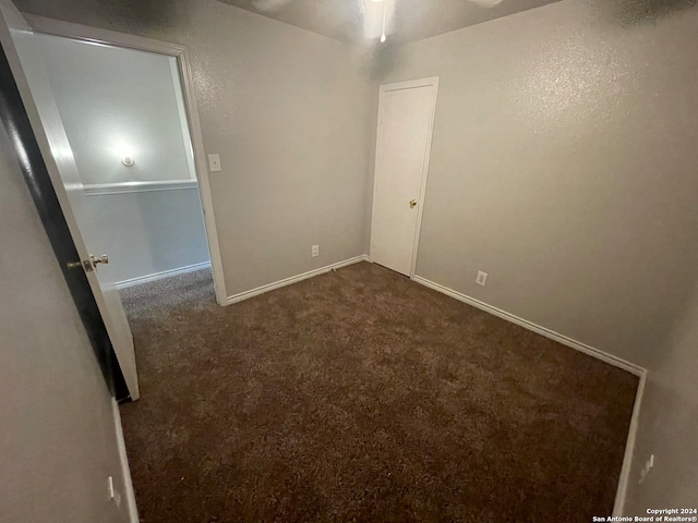 unfurnished room featuring dark carpet