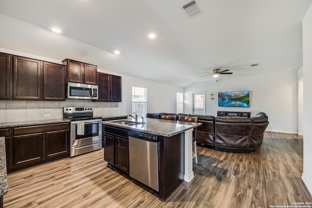 kitchen featuring lofted ceiling, sink, an island with sink, light hardwood / wood-style floors, and stainless steel appliances