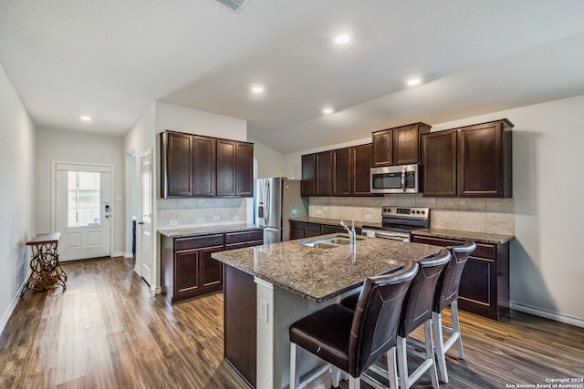 kitchen featuring a kitchen bar, a center island with sink, sink, dark hardwood / wood-style flooring, and stainless steel appliances