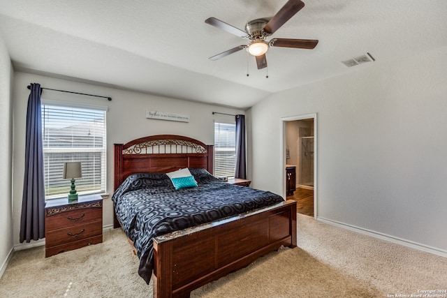 bedroom featuring multiple windows, ceiling fan, ensuite bathroom, and vaulted ceiling