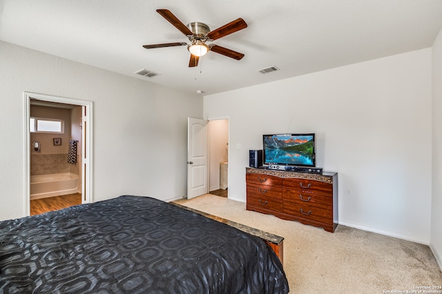 carpeted bedroom with ensuite bath and ceiling fan