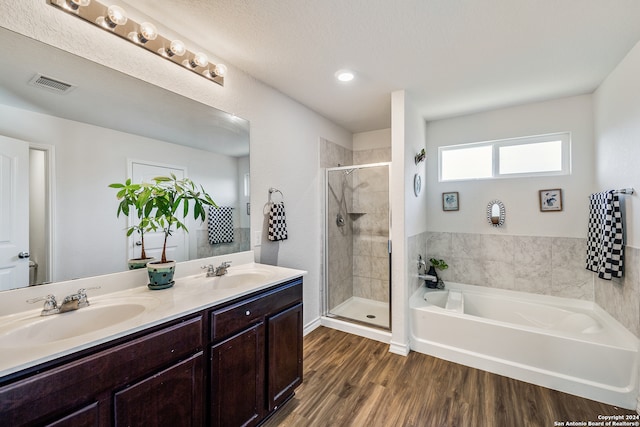 bathroom with a textured ceiling, vanity, wood-type flooring, and shower with separate bathtub