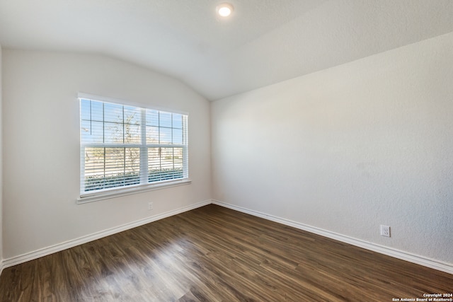 spare room with vaulted ceiling and dark wood-type flooring