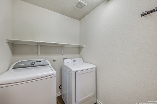 washroom featuring washing machine and dryer and a textured ceiling