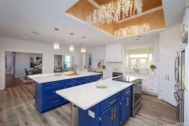 kitchen featuring blue cabinets, white cabinets, stainless steel appliances, and a kitchen island