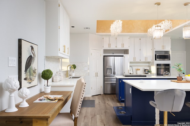 kitchen with stainless steel appliances, blue cabinetry, decorative light fixtures, a notable chandelier, and white cabinets