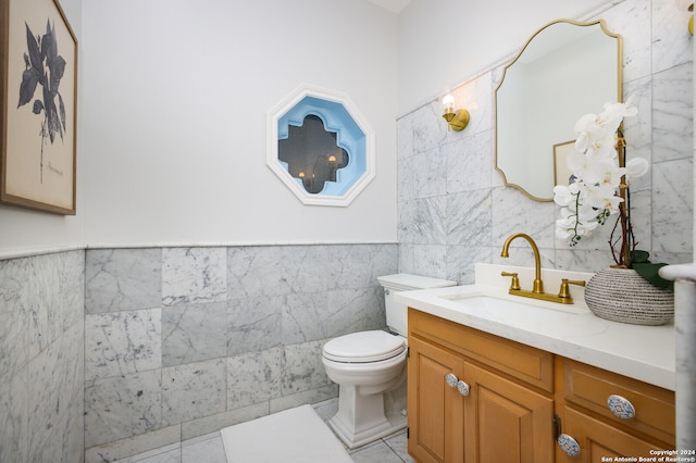 bathroom with tile patterned flooring, vanity, toilet, and tile walls