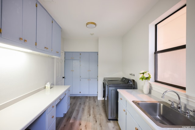 laundry area with cabinets, light wood-type flooring, washer and clothes dryer, and sink