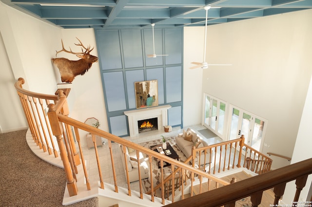 stairway with carpet, ceiling fan, and a towering ceiling